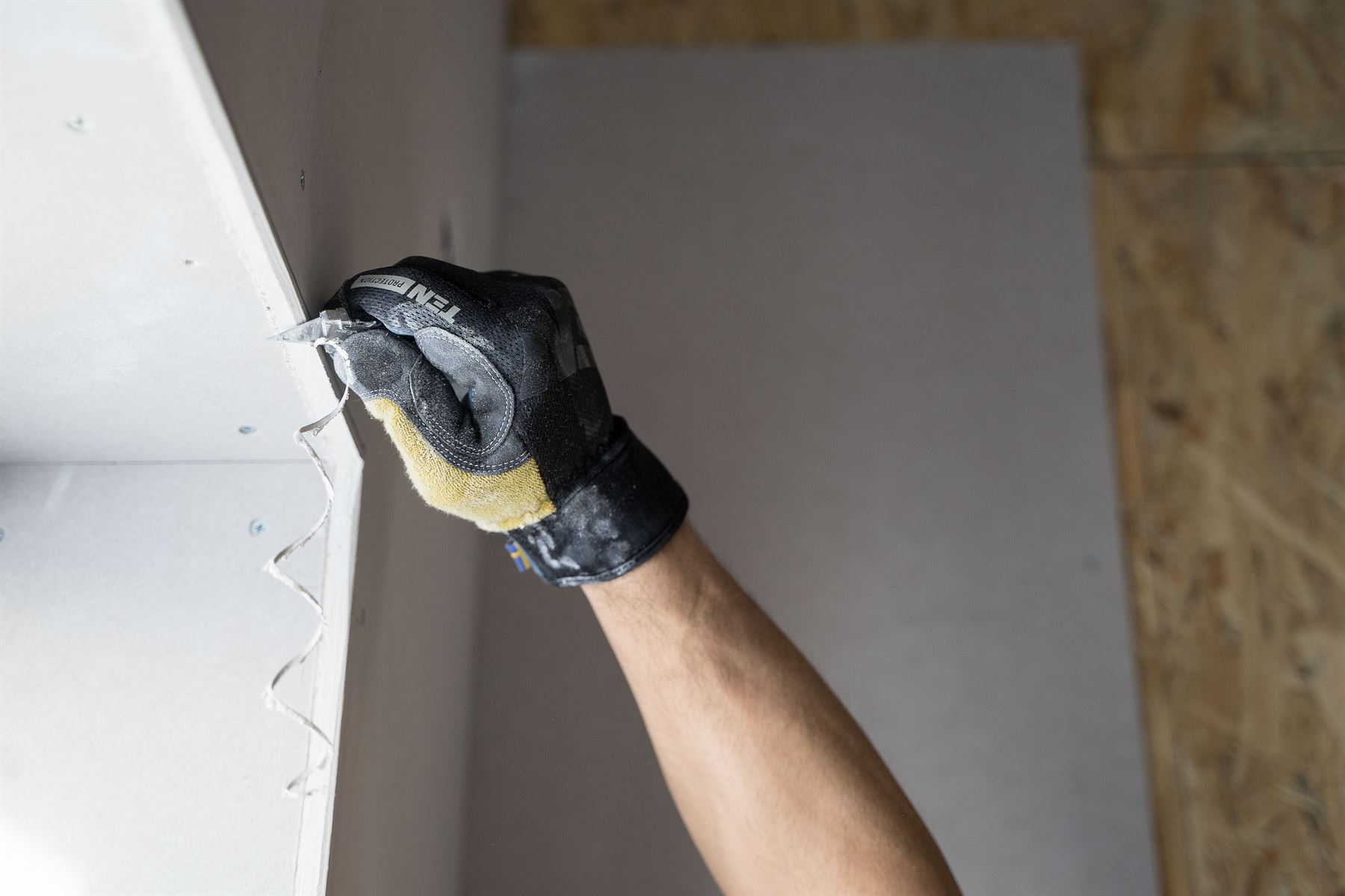 Hand im Arbeitshandschuh an einer Plattenkante